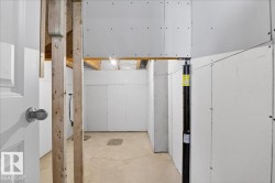 Unfinished lower level with exposed ceiling joists, concrete flooring, drywall-ready walls, and a structural support beam - 