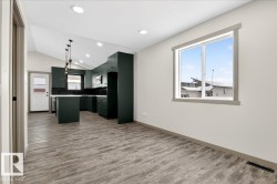 Open-concept living space featuring a modern kitchen with dark cabinetry, white countertops, and a full-height dark tile backsplash - 