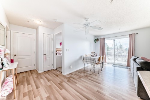 The living area features light-toned flooring, a ceiling fan, and a sliding glass door providing external views - 317 7511 171 Street, Edmonton, AB - Indoor