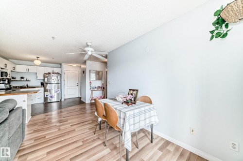 The bright living area features light wood-style flooring and a ceiling fan - 317 7511 171 Street, Edmonton, AB - Indoor