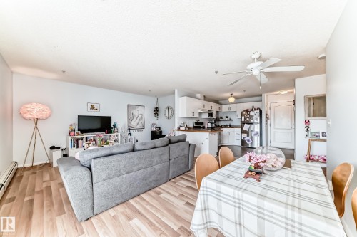 This open-concept living area features light wood-style flooring and light blue walls - 317 7511 171 Street, Edmonton, AB - Indoor