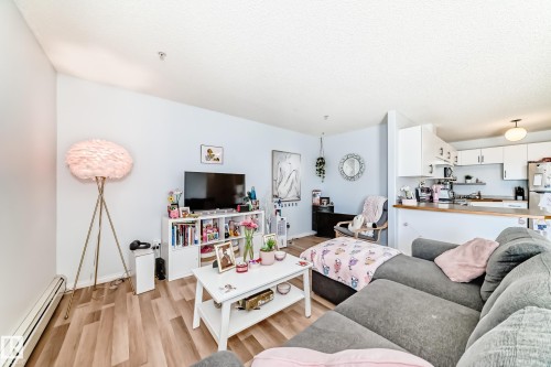 This open-concept living area features light-colored walls and wood-look flooring - 317 7511 171 Street, Edmonton, AB - Indoor Photo Showing Living Room