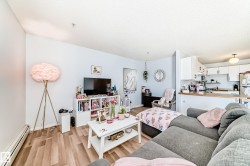 This open-concept living area features light-colored walls and wood-look flooring - 