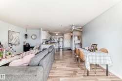The open concept living area features light wood flooring and light-colored walls, creating a bright and airy atmosphere - 