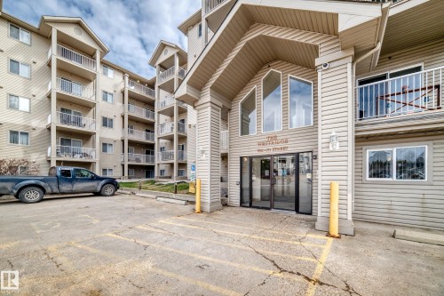 The property features a multi-story building with balconies, a main entrance with glass doors, and large windows on the facade - 317 7511 171 Street, Edmonton, AB - Outdoor With Balcony With Facade