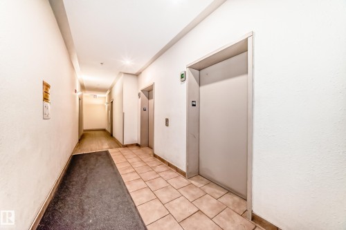 The property features a well-lit hallway with tile flooring, leading to elevator access - 317 7511 171 Street, Edmonton, AB - Indoor Photo Showing Other Room