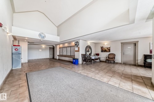 Spacious common area featuring tiled flooring, vaulted ceilings, and decorative wall sconces - 317 7511 171 Street, Edmonton, AB - Indoor Photo Showing Other Room