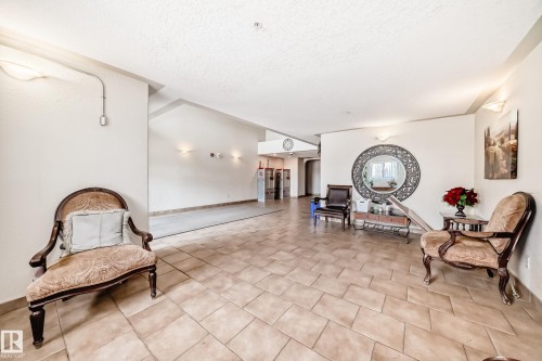 This welcoming common area features tiled flooring, wall sconces, and a decorative mirror - 317 7511 171 Street, Edmonton, AB - Indoor