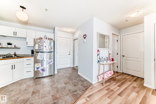 The property features a kitchen with white cabinetry, wooden countertops, and a stainless steel refrigerator - 317 7511 171 Street, Edmonton, AB - Indoor Photo Showing Kitchen