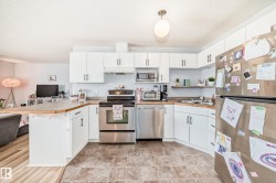 The kitchen features white cabinetry, stainless steel appliances, and a light-toned countertop - 