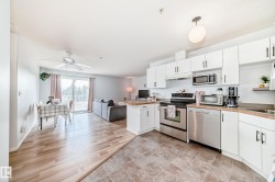 The property features an open concept kitchen and living area with a ceiling fan, light wood-style flooring, and a sliding glass door leading to a balcony - 
