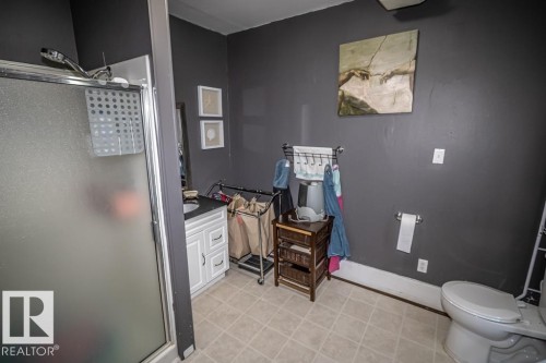 Frosted glass shower enclosure, white vanity with integrated sink, dark countertop, and square floor tiles - 5213 49 Ave, St. Paul Town, AB - Indoor