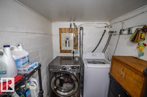 Dedicated laundry area featuring a stainless steel front-load washing machine, a white top-load washing machine, and electrical panel access - 5213 49 Ave, St. Paul Town, AB - Indoor Photo Showing Laundry Room
