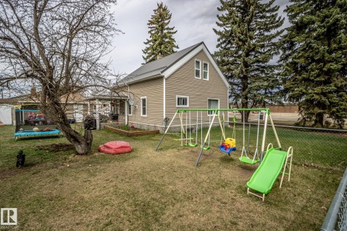 Rear exterior featuring beige siding, a gray metal roof, and white window frames - 5213 49 Ave, St. Paul Town, AB - Outdoor
