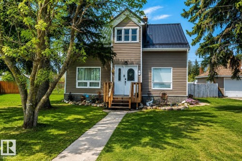 Two-story home featuring tan horizontal siding, a dark metal roof, and white window trim - 5213 49 Ave, St. Paul Town, AB - Outdoor With Facade