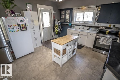 Kitchen featuring a central island with wood countertop, white cabinetry, and a built-in wine rack - 5213 49 Ave, St. Paul Town, AB - Indoor Photo Showing Kitchen With Double Sink