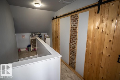 Sliding barn doors featuring natural wood panels and exposed brick accents - 5213 49 Ave, St. Paul Town, AB - Indoor