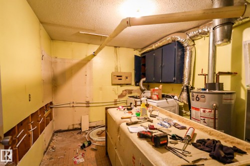 Utility room with exposed wall studs, an exposed water heater, and overhead ductwork - 4114 Main Street, Ashmont, AB - Indoor