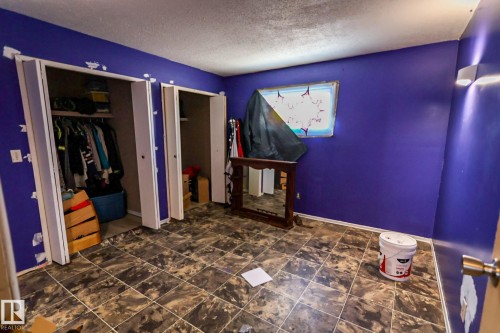 Room featuring patterned tile flooring, dual closet spaces with bi-fold doors, a single window, and wall-mounted light fixtures - 4114 Main Street, Ashmont, AB - Indoor
