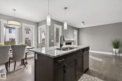 Spacious kitchen island featuring a dual-basin sink, granite countertop, and dark wood cabinetry - 