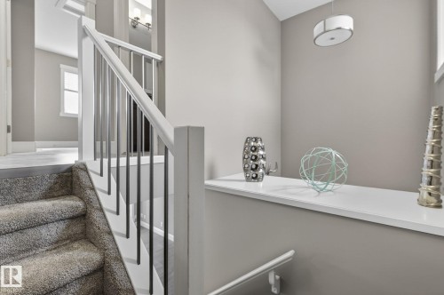 Staircase featuring carpeted treads, white newel posts, and metal balusters - 2017 Westerra Loop, Stony Plain, AB - Indoor Photo Showing Other Room