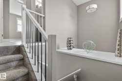 Staircase featuring carpeted treads, white newel posts, and metal balusters - 