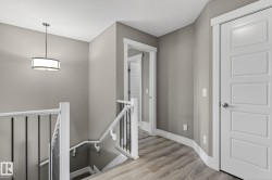 Upper landing featuring wood-finish flooring and a contemporary pendant light fixture - 