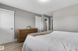 Bedroom featuring light wood-finish flooring, light gray wall paint, and multiple white paneled doors - 