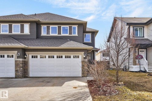 Contemporary townhome featuring a dark gray facade with stone accents, a double-car garage, and multiple large windows - 2017 Westerra Loop, Stony Plain, AB - Outdoor With Facade
