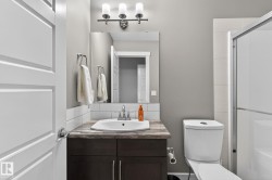 Bathroom featuring a dark wood-finish vanity with a white basin sink, polished chrome faucet, and a stone-finish countertop - 