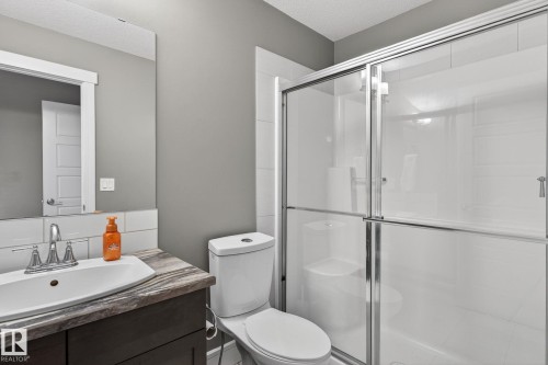 Bathroom featuring a glass-enclosed shower, white subway tile backsplash, a vanity with a rectangular sink, a dark wood-finish cabinet, and a framed mirror - 2017 Westerra Loop, Stony Plain, AB - Indoor Photo Showing Bathroom