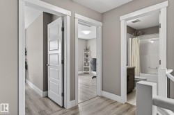 Upper-level hallway featuring wood-finish flooring, neutral wall paint, and white trim - 