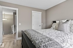 Bedroom featuring neutral wall paint, wood-finish flooring, a white five-panel interior door, and white trim throughout - 