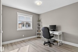 Neutral-toned room featuring wood-finish flooring, a single window with blinds, and white trim - 