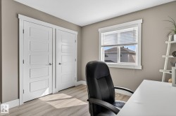 Bright room featuring a window with horizontal blinds, wood-finish flooring, and two paneled white doors with chrome hardware - 