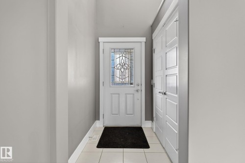 Entryway featuring a white door with decorative glass inserts, white trim, light gray walls, and light-toned tile flooring - 2017 Westerra Loop, Stony Plain, AB - Indoor Photo Showing Other Room