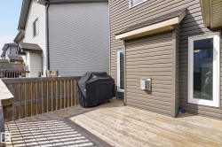 Spacious wood deck with natural wood railing, featuring a brown vinyl-sided exterior and white-framed windows - 