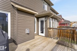 Expansive wood deck featuring a full-light exterior door, multiple windows, brown horizontal siding, and a wood railing - 