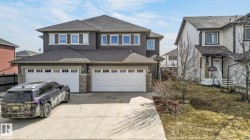Two-story residence featuring dark siding with stone accents and multiple large windows - 
