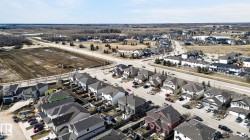 Aerial perspective showcasing a developed residential neighborhood with a mixture of single-family homes and townhomes, featuring paved roads and sidewalks - 