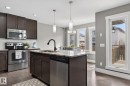 Modern kitchen featuring dark wood cabinetry, stainless steel appliances, granite countertops, an island with an undermount sink and black faucet, and pendant lighting - 2017 Westerra Loop, Stony Plain, AB  - Indoor Photo Showing Kitchen With Upgraded Kitchen 