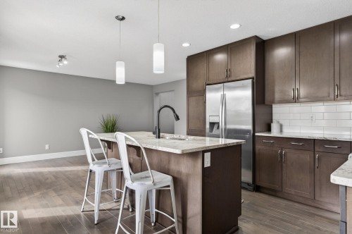 Contemporary kitchen featuring dark wood-finish cabinetry, stainless steel appliances, and light-toned countertops - 2017 Westerra Loop, Stony Plain, AB - Indoor Photo Showing Kitchen With Upgraded Kitchen