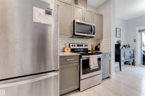 Kitchen featuring stainless steel appliances, grey cabinetry, light countertops, and a subway tile backsplash - 11 4835 Wright Drive, Edmonton, AB - Indoor Photo Showing Kitchen