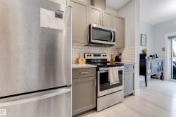 Kitchen featuring stainless steel appliances, grey cabinetry, light countertops, and a subway tile backsplash - 