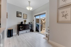 Light wood-finish flooring extending from a built-in sideboard with glass-front cabinetry - 