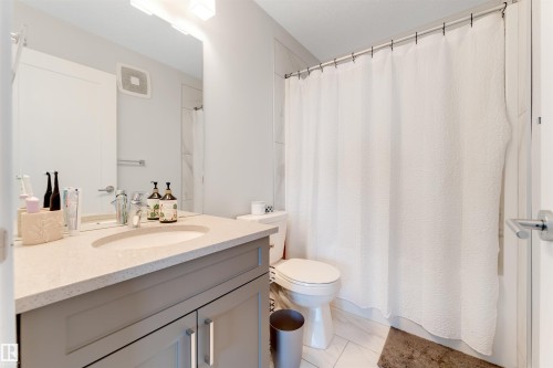 Bathroom featuring a vanity with an integrated sink, light-toned countertop, and gray cabinetry - 11 4835 Wright Drive, Edmonton, AB - Indoor Photo Showing Bathroom