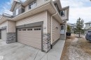 This property features a beige exterior with stone accents, a two-car garage with paneling and windows, and a concrete driveway - 11 4835 Wright Drive, Edmonton, AB  - Outdoor 