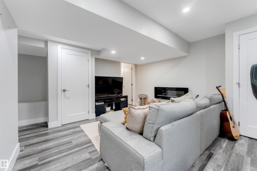 Spacious recreation room featuring wood-finish flooring, recessed lighting, white trim, and a modern electric fireplace - 11 4835 Wright Drive, Edmonton, AB - Indoor