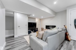 Spacious recreation room featuring wood-finish flooring, recessed lighting, white trim, and a modern electric fireplace - 