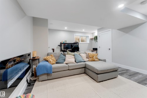 Finished lower level featuring recessed lighting, a white paneled door with brushed nickel hardware, light gray walls, and wood-finish flooring - 11 4835 Wright Drive, Edmonton, AB - Indoor Photo Showing Living Room
